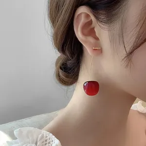 Detailed view of red cherry earrings worn by model showing sweet elegant style