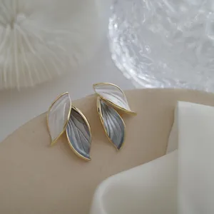 Close-up of minimalist two-leaf earrings featuring elegant white and grey enamel details