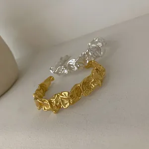 Detailansicht der zerknitterten Lavatextur auf gold- und silberfarbenen Armreifen