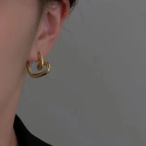 Primo piano di un elegante orecchino a cerchio dorato a forma di cuore su un modello