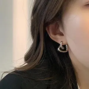 Primo piano di un orecchino a cerchio a cuore d'argento indossato da una modella