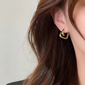 Dettaglio di un orecchino a cerchio a forma di cuore d'oro indossato da una modella.