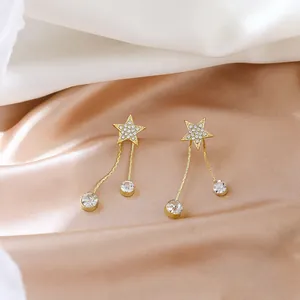 Élégantes boucles d'oreilles étoiles dorées avec de fins glands en cristal sur soie.