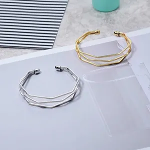 Détail de bracelets joncs géométriques superposés minimalistes en or et argent