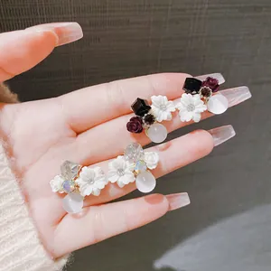 Dettaglio ravvicinato di eleganti orecchini a fiore vintage con zirconi e perle opale