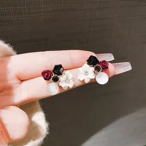 Dettaglio di orecchini a fiore vintage con zircone e piccoli fiori di rosa scura
