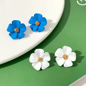 Dettaglio ravvicinato di orecchini a lobo a forma di fiore opaco blu e bianco dorato.