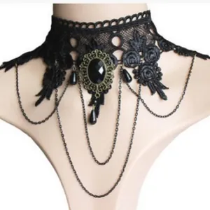 Elegante girocollo in pizzo gotico nero con gemma vintage e dettagli a catena drappeggiata.