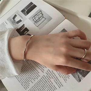 Detailed view of a silver twisted bangle and ring on a hand with an artistic book background