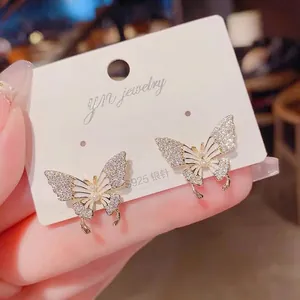 Primo piano di eleganti orecchini a farfalla con micro-zirconi e perle raffinate