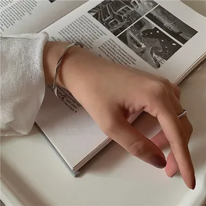 Close-up of a minimalist silver wave-patterned open bangle on a hand