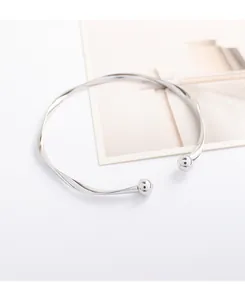 Close-up detail of silver wave pattern open cuff bracelet with spherical ball ends