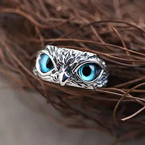 Primo piano dettagliato di un anello a gufo in argento vintage con occhi blu vivaci