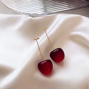 Close-up detail of sweet red cherry earrings with elegant golden metal stems finish