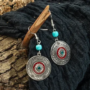 Dettaglio di orecchini pendenti etnici bohémien con smalto rosso e perline turchesi