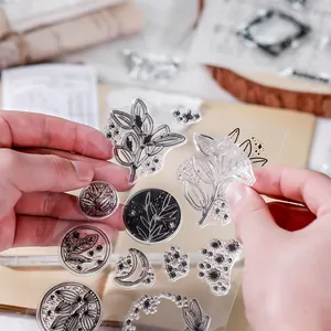 Close-up of vintage clear silicone stamp sheet with botanical patterns held by hands