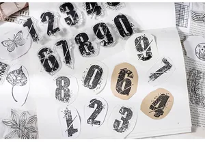 Close-up of retro distressed number and botanical transparent stamps on a white notebook
