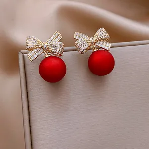 Orecchini a fiocco con pavé di cristalli e perle rosse opache per uno stile festivo.