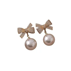 Eleganti orecchini a fiocco dorati con strass pavé e pendente a perla per donna moda