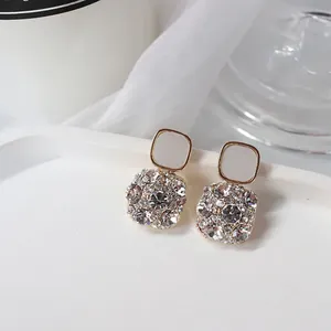 Primo piano di eleganti orecchini quadrati con strass scintillanti e intarsio grigio.