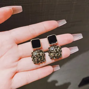 Dettaglio di eleganti orecchini quadrati a goccia con smalto nero e strass