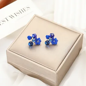 Dettaglio di eleganti orecchini a lobo blu con fiori, cristalli e motivi a rosa