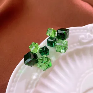 Dettaglio di orecchini a lobo in zircone verde smeraldo sfaccettato su un piatto.