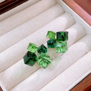 Dettaglio di orecchini a cubo geometrici con cristalli di zircone verde sfumato.