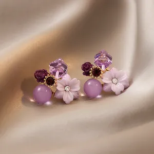 Dettaglio macro di orecchini vintage a bottone con fiori di zircone viola su seta
