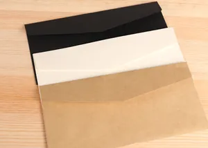 Close-up of Western No.5 blank envelopes in kraft, black, and beige on wood table.