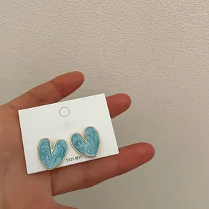Detailopname van blauwe marmeren hartoorbellen met S925 zilveren naalden op kaart.