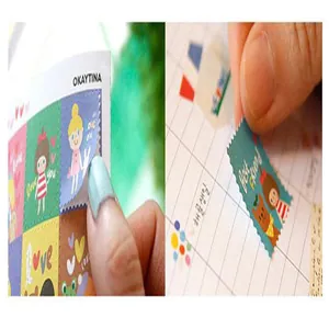 Gros plan de mains appliquant de jolis autocollants de timbres sur une page de journal.