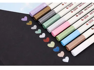Close-up view of STA metallic paint pens showing various vibrant colors on black paper surface