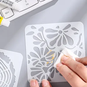 Reusable white PET plastic floral drawing stencil template being wiped clean by hand