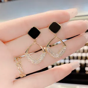 Detailed view of elegant geometric gold-toned earrings with black studs and pavé crystals