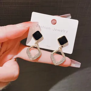 Detail view of gold-toned geometric earrings with black square and rhinestones