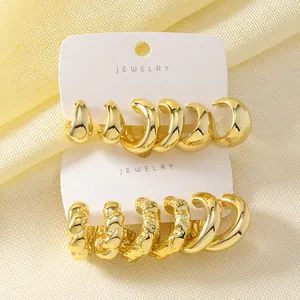 Detail view of chunky gold hoop earrings with twisted and smooth water drop textures.
