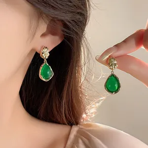 Dettaglio di orecchini a goccia verdi con finitura dorata in stile coreano elegante