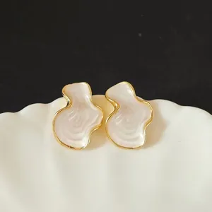 Macro-opname van vintage wolkvormige oorknopjes met wit emaille en gouden randen