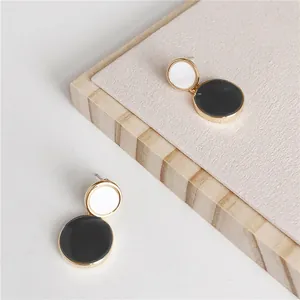 Detail view of Korean style black and white round drop oil earrings with gold edges.