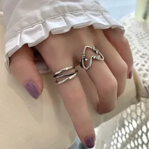 Close-up of S925 sterling silver hollow heart and triple-layered band rings on hand.
