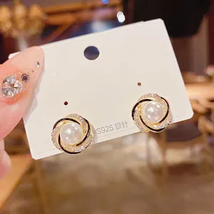 Primo piano di orecchini a perno con perla stile francese, strass e smalto nero