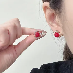Primo piano di orecchini francesi con perla rossa e cornice dorata scintillante.