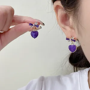 Close-up detail of lavender purple heart drop earrings featuring elegant crystal bow design