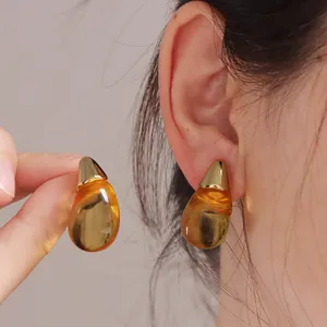 Dettaglio degli orecchini a goccia in resina ambrata con eleganti perni in metallo