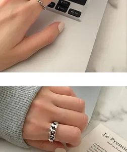 Close-up view of a retro silver cuban chain ring and thin beaded metal band on a hand