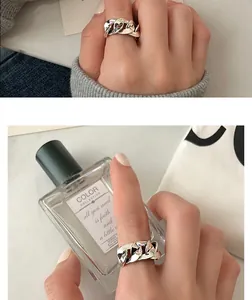 Close-up view of a retro chunky braided silver ring worn on a hand in lifestyle setting.