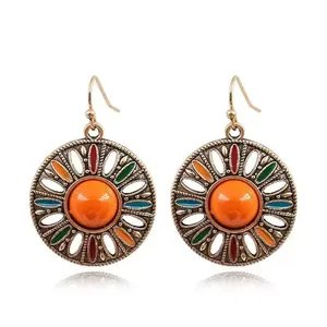 Dettaglio di orecchini vintage bohémien con smalto colorato e pietra centrale arancione