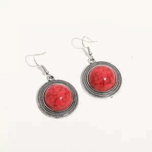 Dettaglio di orecchini pendenti boho vintage con pietre rosse tonde e bordi d'argento