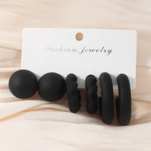 Close-up of matte black earring set featuring C-shaped and twisted hoop designs